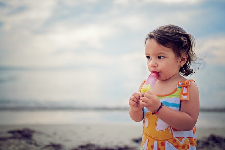 Baby girl is eating ice cream on the beach