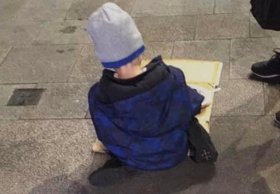 Five-year-old boy eating dinner from a sheet of cardboard shows reality of the homeless crisis